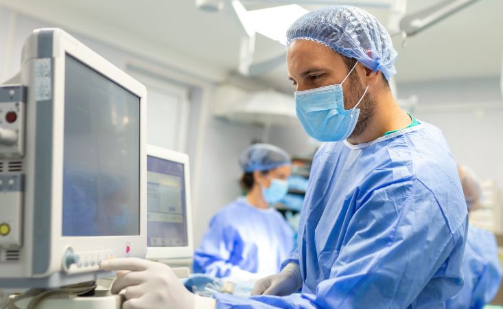 Ärzte im OP. Ein Arzt blickt auf einen Monitor.