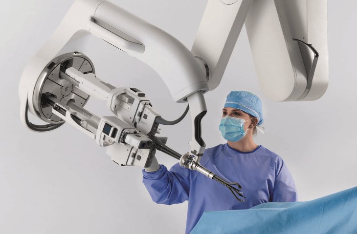 Eine Person steht an einem OP-Tisch und richtet den Blick auf einen OP-Roboter