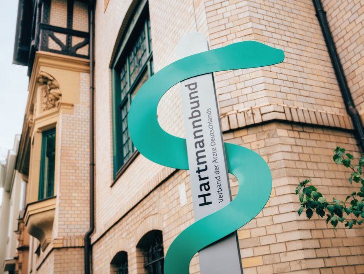 Nahaufnahme einer alten Villa mit Backsteinfassade. Davor ein Firmenschild