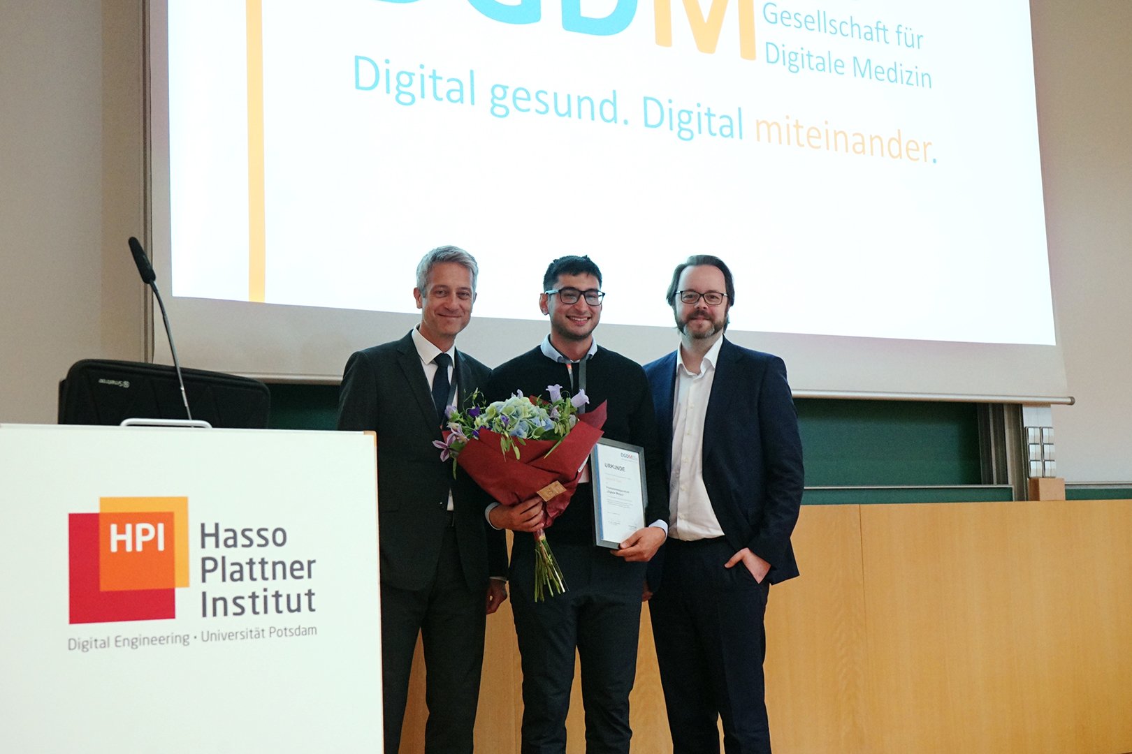 Vergabe der Urkunde an Gürcan Özden. V.l.n.r.: Timmy Klebb (DÄF), Gürcan Özden und Sebastian Schulz (DGDM)