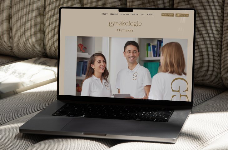 Ein Notebook steht aufgeklappt auf einem Sofa. Der Monitor zeigt eine Website