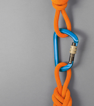 Ein blauer Karabinerhaken verbindet zwei orangefarbene Kletterseile.