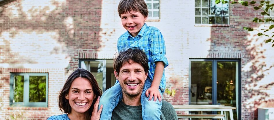 Eine Familie steht im Garten vor ihrem Haus